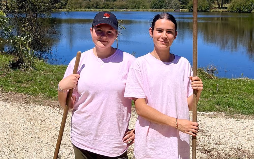 Emmy Gravelat et Emma Bessaguet, râteau en main, au bord du plan d’eau (photo Charente Libre)